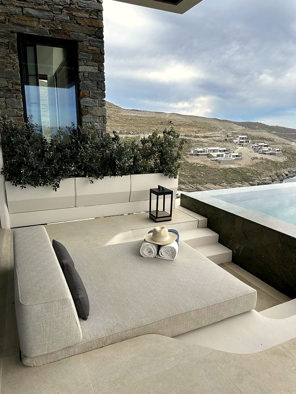 One&Only Aesthesis, Greece — terrace daybed with rolled towels, infinity pool and Aegean view.