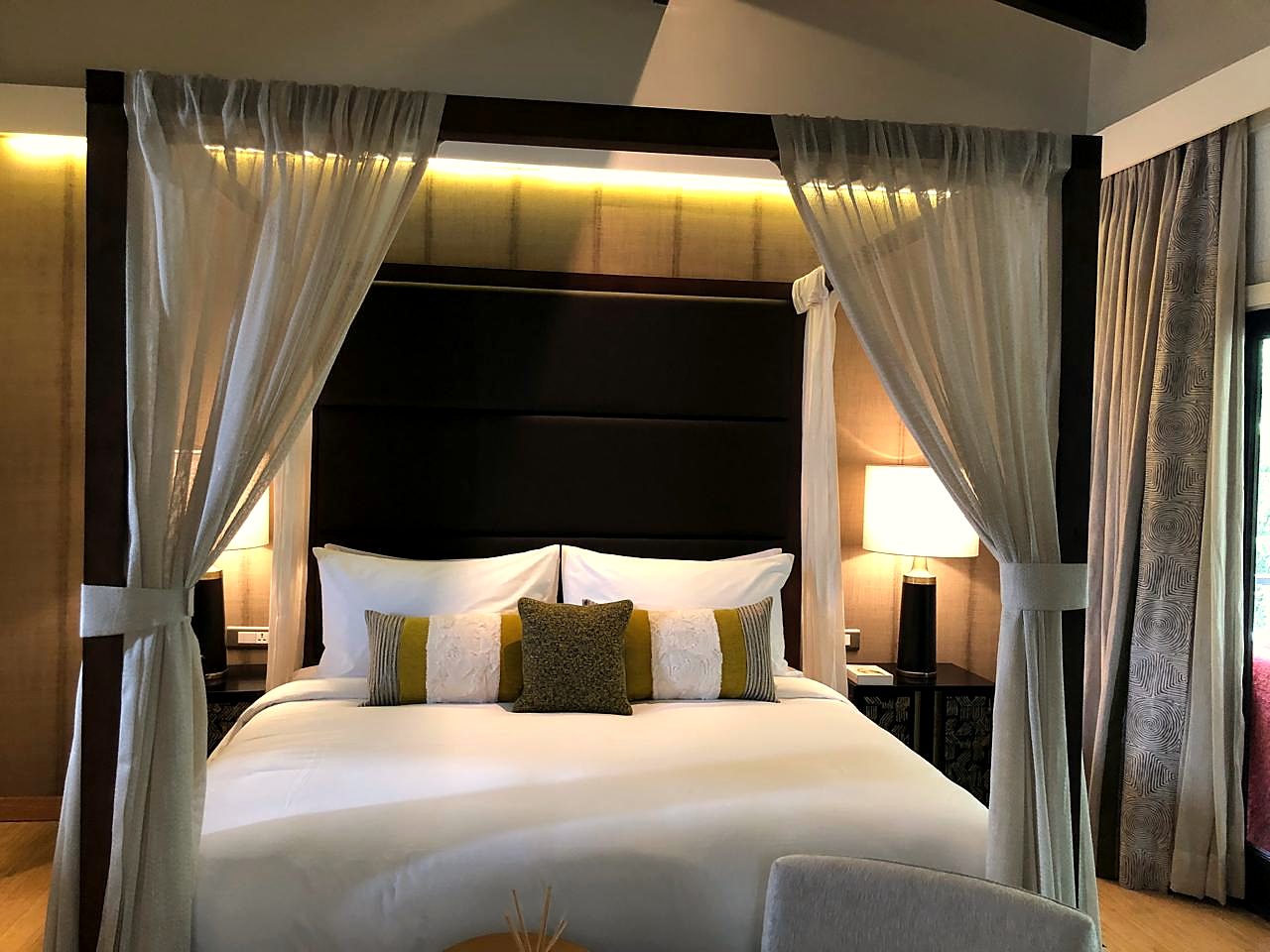 Four-poster canopy bed, made to standard at twilight inside a suite at a property we operate with.